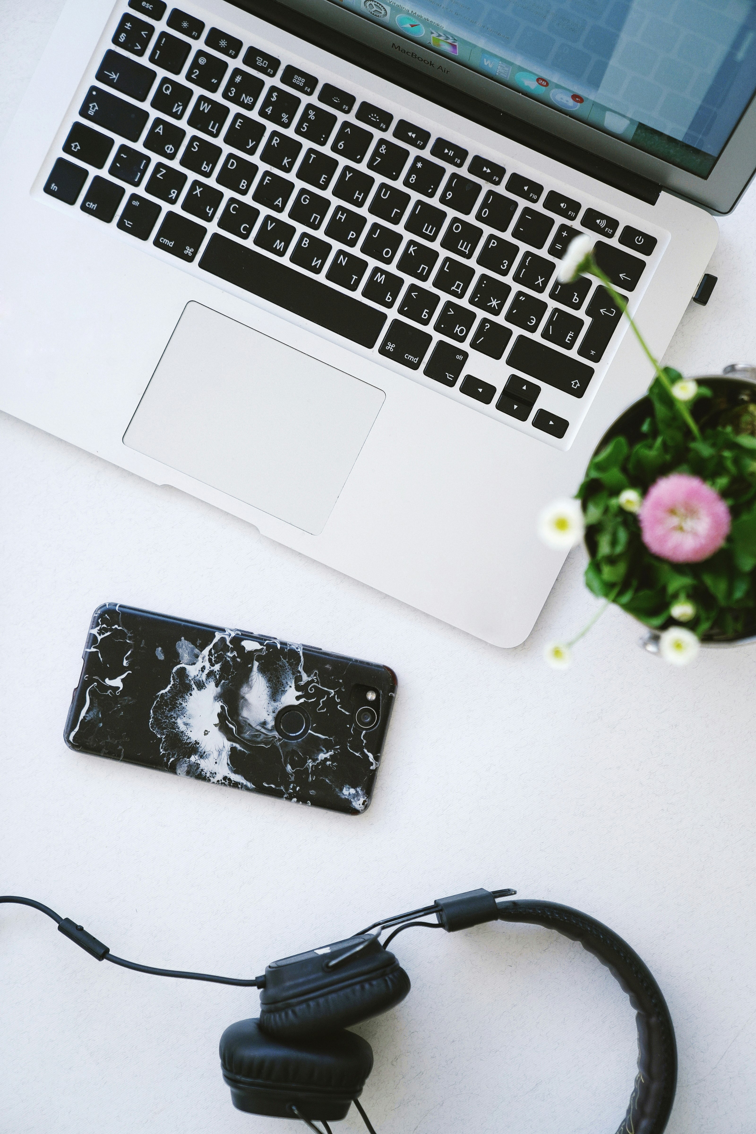 black headphones, smartphone and MacBook on table